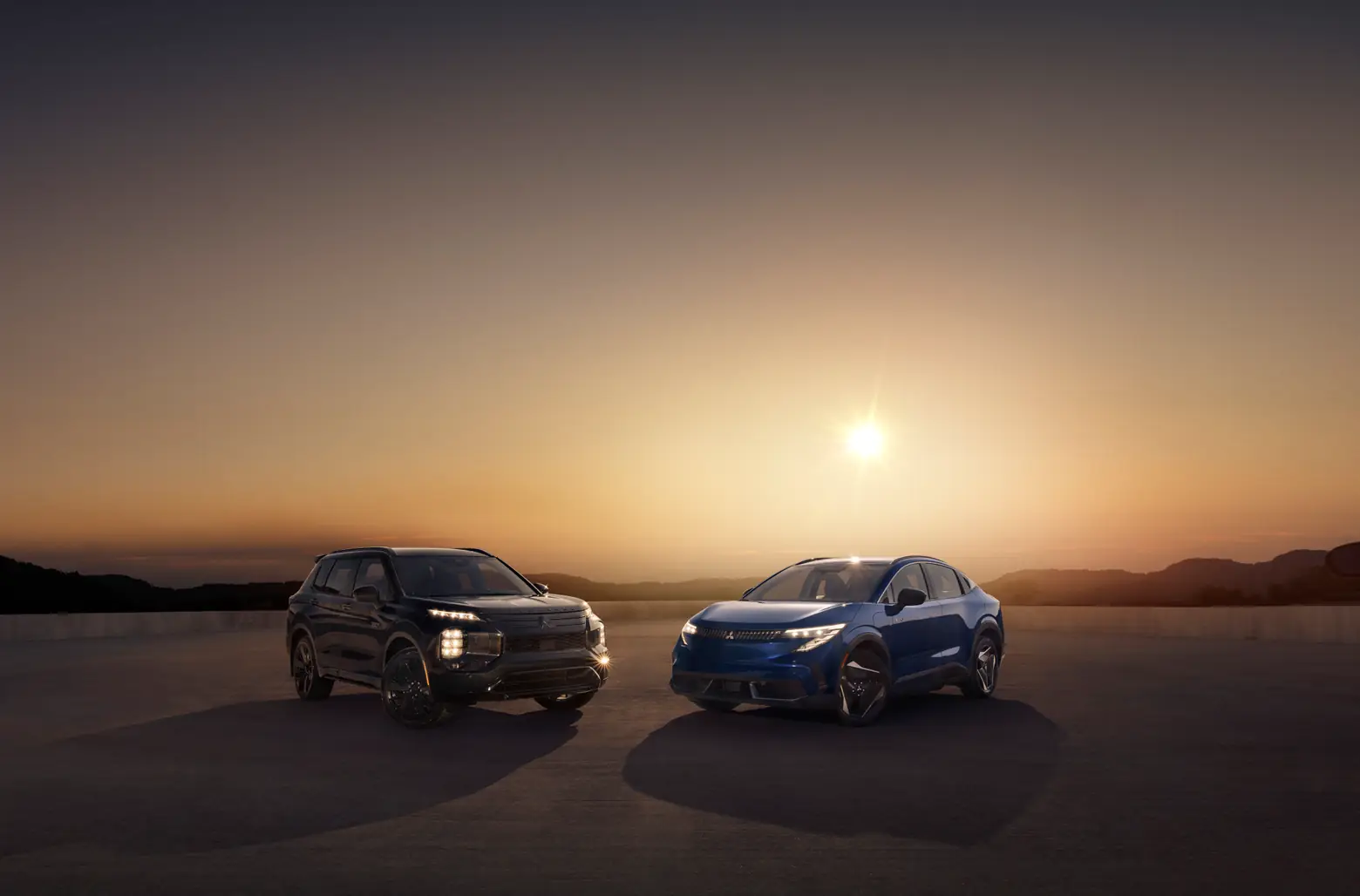 Two 2027 Eclipse Sportback EVs in front of a sunset on a mountain